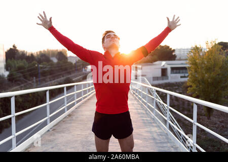 Jogger with smartphone in arm pocket with arms raised Stock Photo