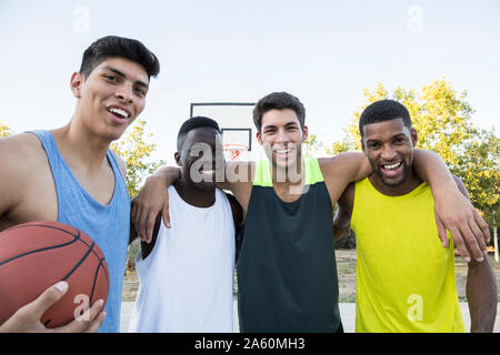 Group of multiracial men in sportswear with ball on sports ground Stock Photo