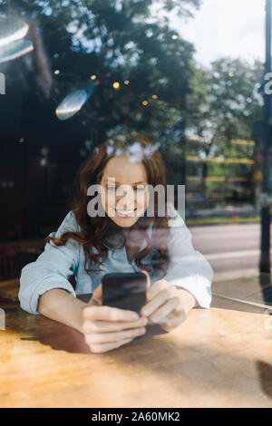 Happy redheaded woman with cell phone in a cafe Stock Photo