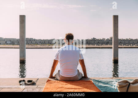 Young man sitting on a pier at the sea Stock Photo