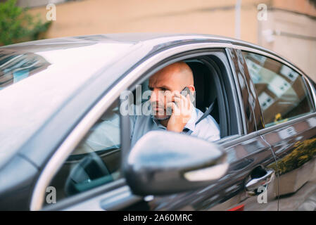 Businessman driving vehicle and using smartphone Stock Photo