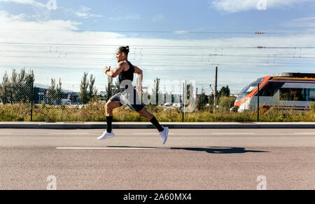 Sporty young man running on a road Stock Photo