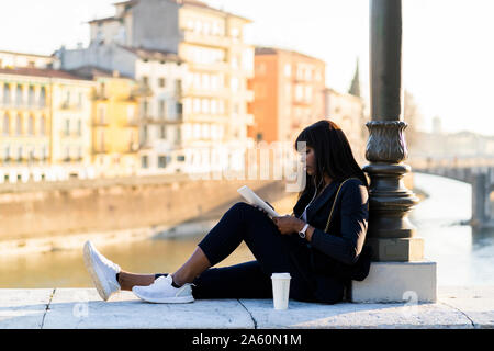 Businesswoman sitting outdoors using a digital tablet Stock Photo