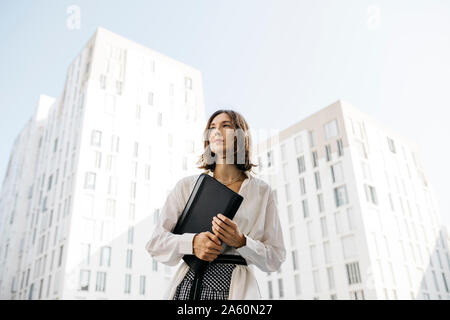 Serious woman carryiing folder in the city Stock Photo