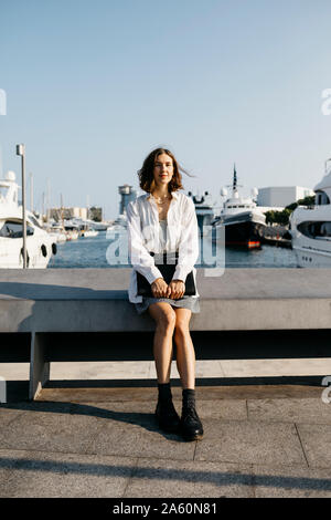 Pretty businesswoman sitting at the marina after work, relaxing Stock Photo