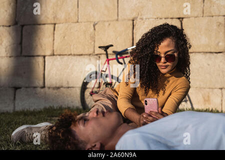 Young woman taking smartphone pictures of her boyfriend Stock Photo