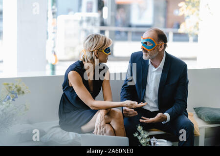 Businessman and woman wearing super hero masks, trying to find solutions Stock Photo