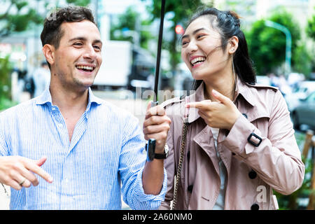 Happy couple with umbrella having fun in Ginza, Tokyo, Japan Stock Photo