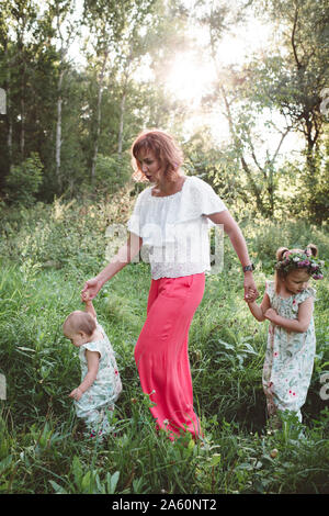 Mother with two daughters walking in a meadow Stock Photo