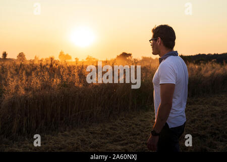 Organic farmer looking over wheat field at sunset