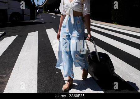 Close-up of young woman with baggage crossing a street at the airport Stock Photo