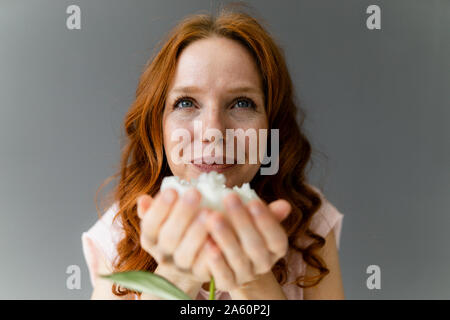 Portrait of redheaded woman smelling white peony Stock Photo