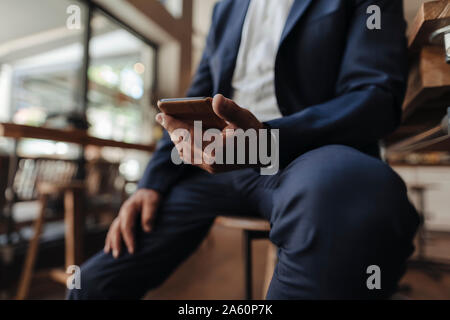 Close-up of businessman holding cell phone in a cafe