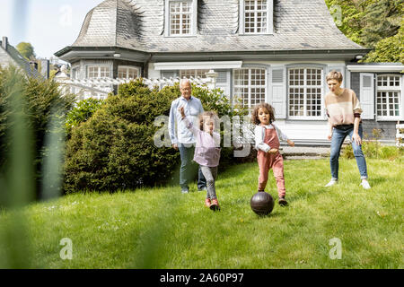 Happy extended family playing football in garden Stock Photo