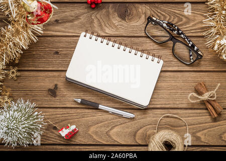 Blank notebook on  wood background with Christmas ornaments decorations. Mockup Christmas background with notebook for wish list or to do list. Flat l Stock Photo