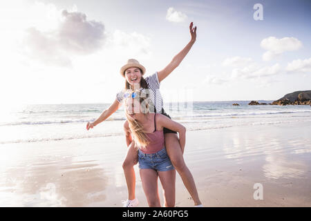 Two girlfriends having fun, carrying each other piggyback Stock Photo