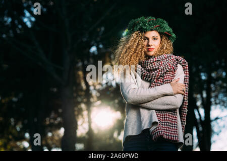 Portrait of young woman wearing Christmas wreath on her head Stock Photo