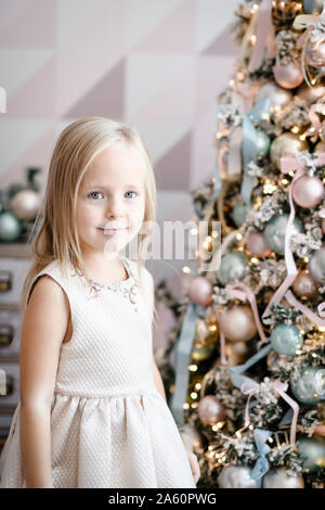 Portrait of smiling little girl standing in front of lighted Christmas tree Stock Photo