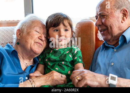 Grandparents spending time with the granddaughter in living room Stock Photo