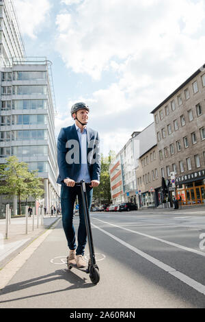 Young businessman riding e-scooter on bicycle lane in the city Stock Photo