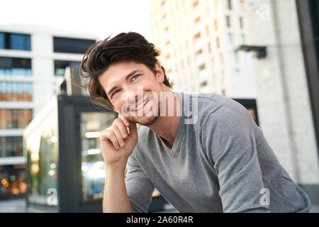 Portrait of smiling man wearing grey shirt in the city Stock Photo