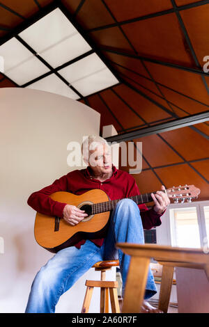 Senior man playing guitar at home Stock Photo