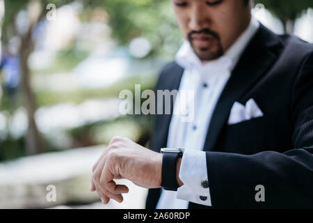 Young businessman in the city checking his smartwatch Stock Photo