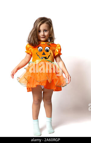 A little girl dressed in an orange pumpkin dress standing up against a  white background Stock Photo - Alamy