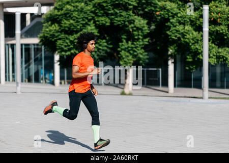 Young man jogging in the city, listening to music Stock Photo