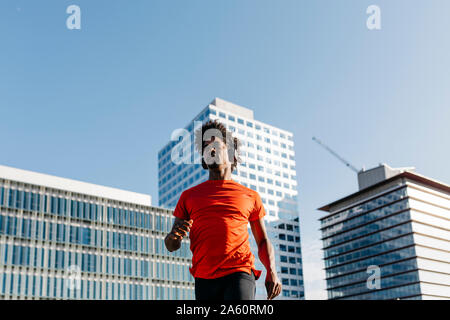 Young man jogging in the city, listening to music Stock Photo