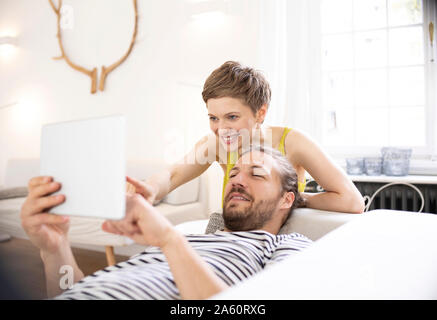 Happy young couple with tablet in living room at home Stock Photo