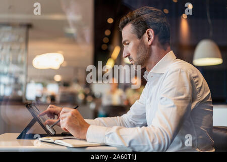 Businessman using tablet and taking notes in a cafe Stock Photo