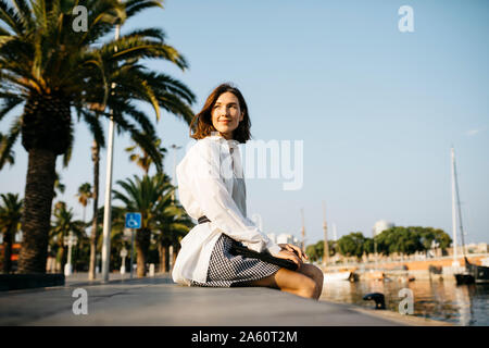 Pretty businesswoman sitting at the marina after work, relaxing Stock Photo