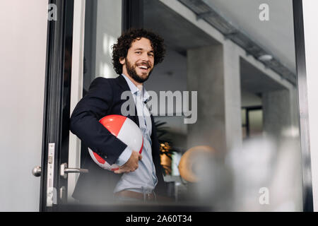 Happy businessman holding beach ball in office Stock Photo