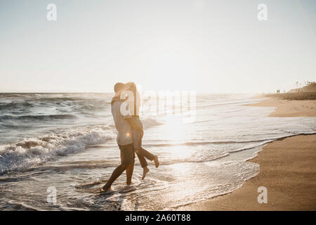 Affectionate young couple hugging at the seashore at sunset Stock Photo
