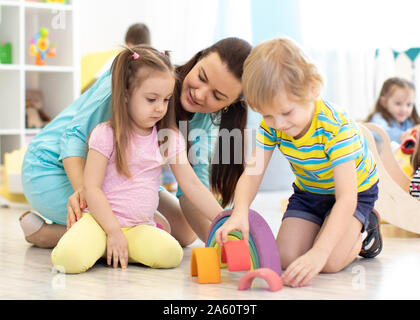 Preschool children and kindergarten teacher playing with wooden toys Stock Photo