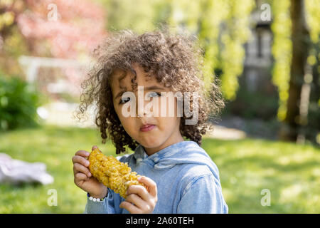Portrait of boy eating a corn cob in garden Stock Photo