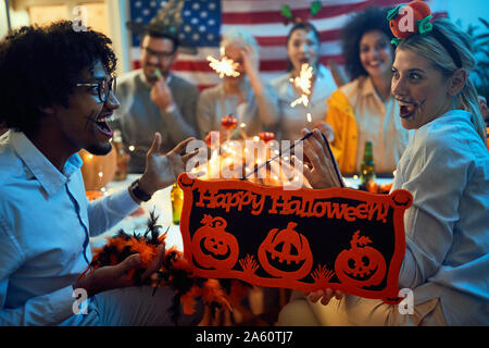 smiling friends dressed in scary costumes celebrating Halloween Stock Photo