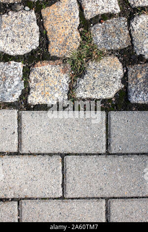 Old and new cobblestones, with grass growing in between Stock Photo