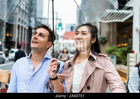 Happy couple with umbrella in Ginza, Tokyo, Japan Stock Photo