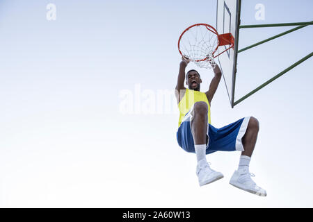 Man in sportswear hanging on hoop and shouting Stock Photo
