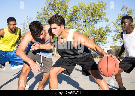 Young men playing basketball and dribbling ball on sports ground Stock Photo