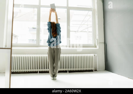 Back view of woman in a loft doing stretching exercise Stock Photo