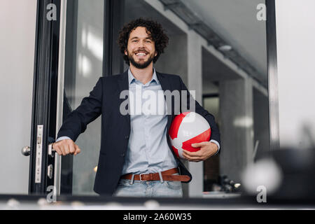 Happy businessman holding beach ball in office Stock Photo