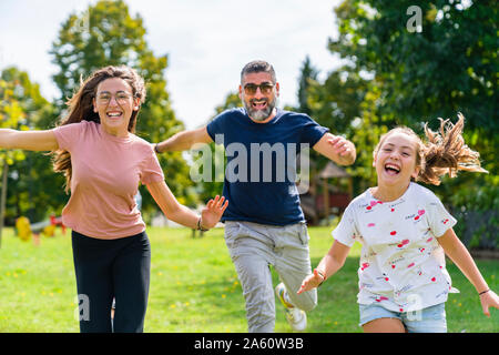 Carefree father with two daughters running on a meadow Stock Photo