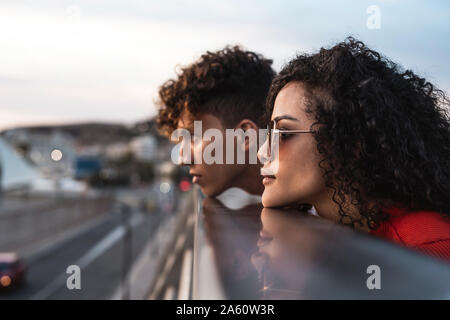 Young couple on bridge, resting chins on railing Stock Photo