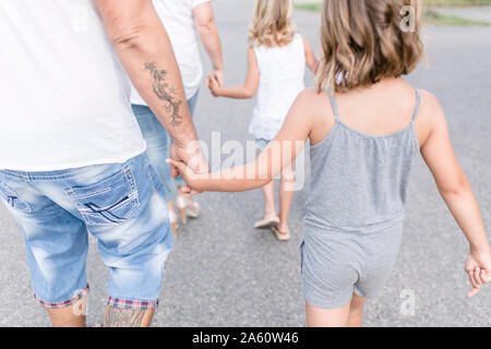 Rear view of family walking hand in hand on a road