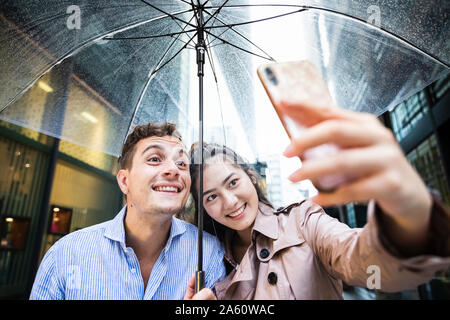 Happy couple with umbrella taking a selfie in Ginza, Tokyo, Japan Stock Photo