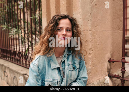 Beautiful young woman with curly hair and glasses in the city Stock Photo