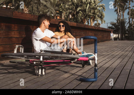Young couple with bicycle sitting in the city, talking Stock Photo